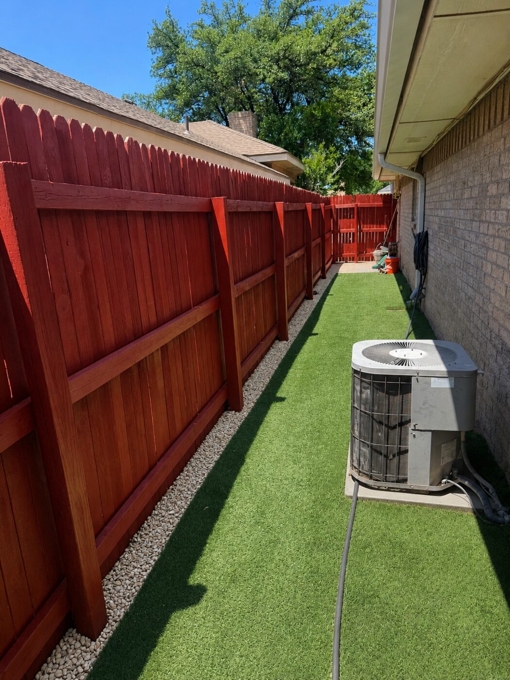 Freshly stained wood fence with artificial turf and decorative rock